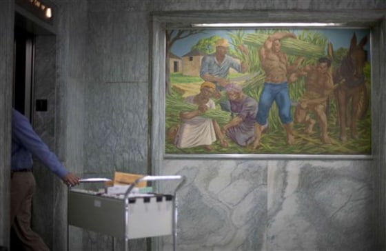 One of seven historic paintings hangs in the lobby of the Georgia Department of Agriculture as an employee pulls a filing cabinet into an elevator on Tuesday, Dec. 28, in Atlanta. Incoming Georgia agriculture commissioner Gary Black wants to remove the paintings, including one depicting idealized versions of slavery, and put them into storage when he takes office next month.